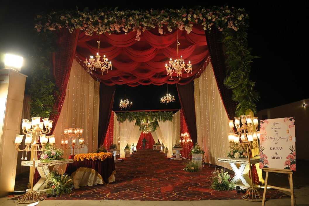 Red and gold mandap entrance with chandeliers at a Lucknow wedding by Tathastu Events