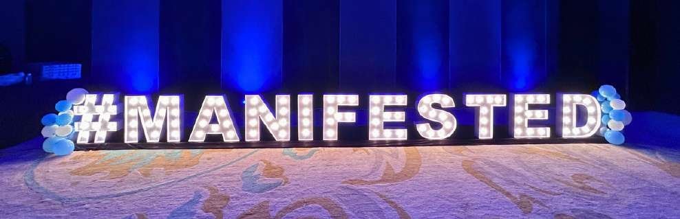Illuminated MANIFESTED marquee letters at a social event in Lucknow